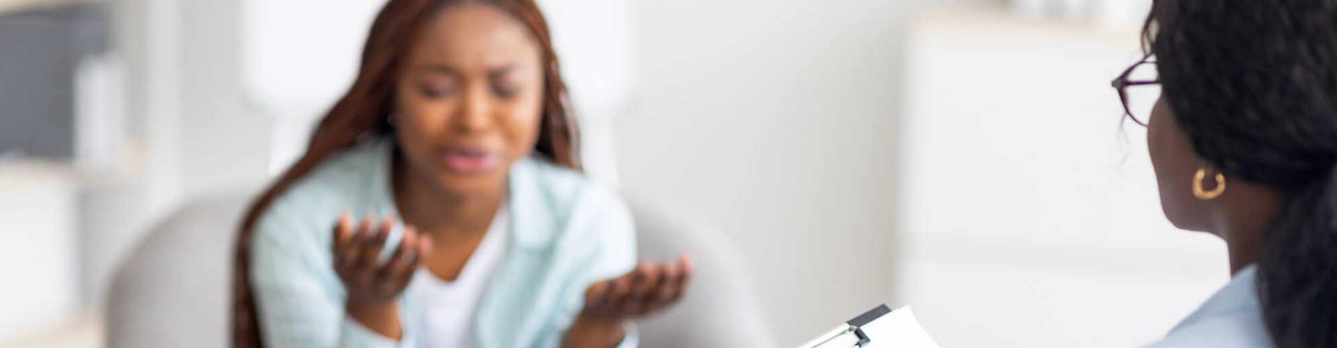 a woman in a white shirt and a woman in a black shirt sharing experiences during group therapy